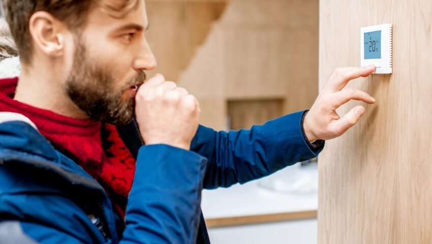 Man looking at thermostat in home