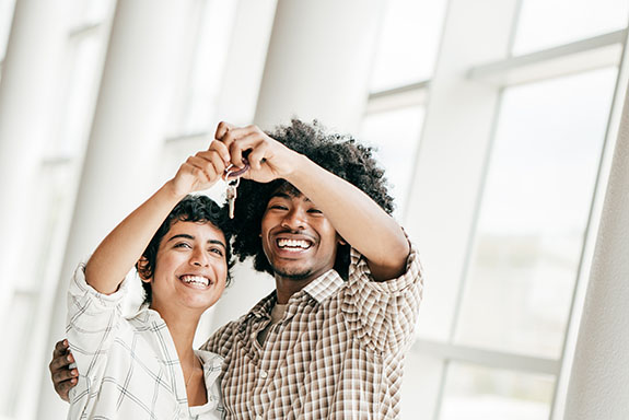 Renters insurance. Young couple holding up keys to their new apartment