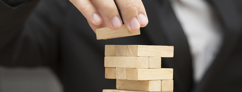 Businessman placing wooden block on a tower. Risk and strategy in business concept