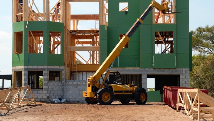 how-much-does-it-cost-to-build-a-house-in-canada Framework of a house with boom lift