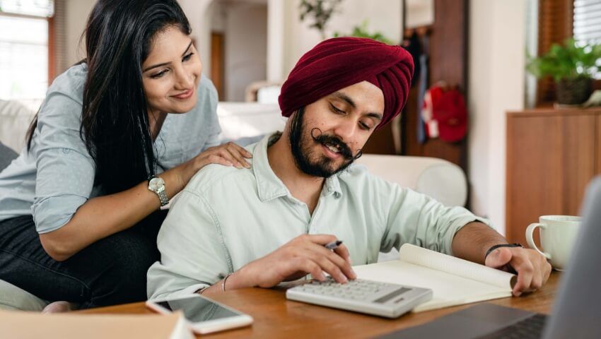 Woman looking over man's shoulder working with calculator