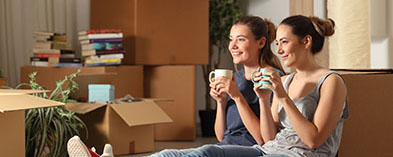 two women drinking coffee resting, moving boxes